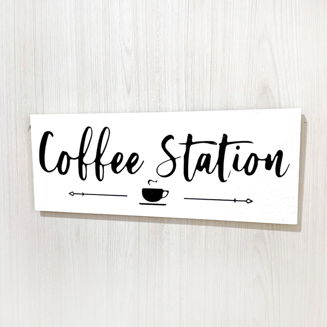 Cuadro fondo blanco y texto Coffee Station color negro con una taza.