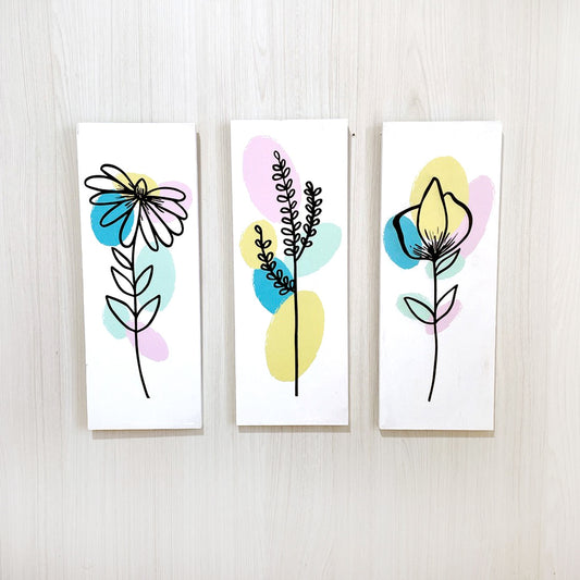 Set de cuadros decorativos florales. Una con una margarita, otra con dibujo de un trigo y un dibujo de tulipan. Las tres con colores de fondo. 